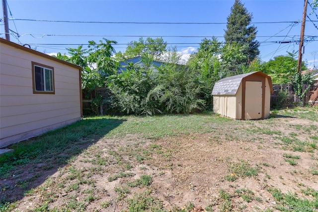 view of yard featuring an outbuilding, a shed, and fence