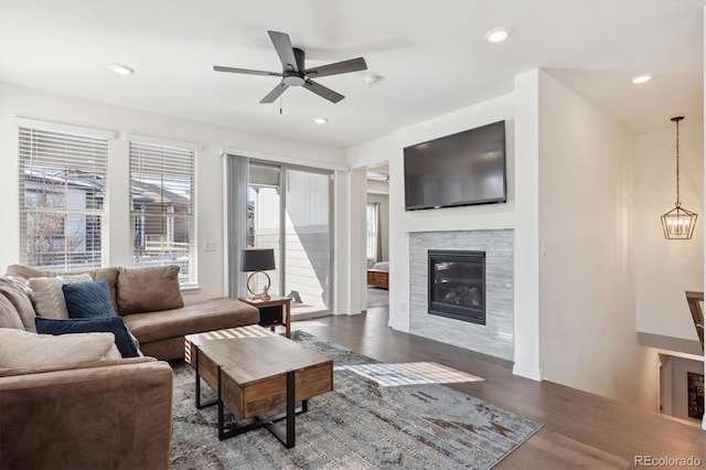 living room with dark wood-type flooring, a tile fireplace, and ceiling fan