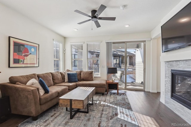 living room featuring ceiling fan, dark hardwood / wood-style flooring, and a tiled fireplace