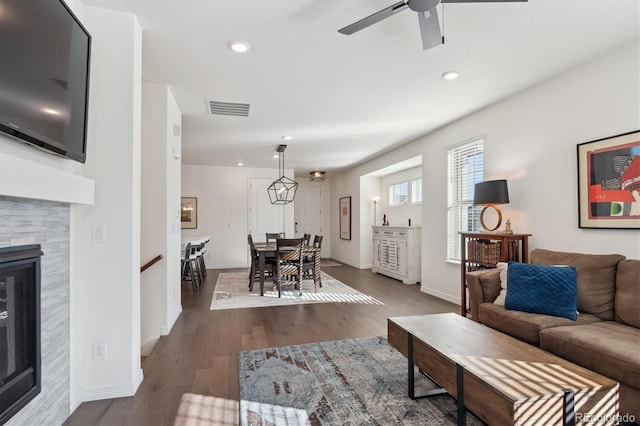 living room with ceiling fan, dark hardwood / wood-style floors, and a tile fireplace