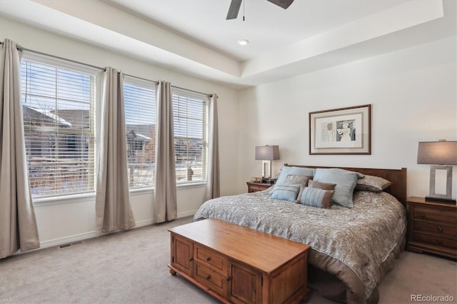 carpeted bedroom featuring ceiling fan and a tray ceiling