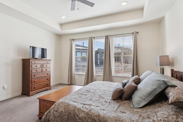 carpeted bedroom with ceiling fan and a tray ceiling