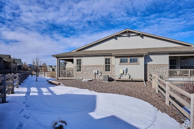 snow covered property with a porch and central air condition unit