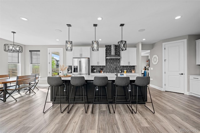 6737 S White Crow Way, Aurora, CO 80016 - kitchen featuring stainless steel fridge, wall chimney exhaust hood, light wood finished floors, light countertops, and recessed lighting