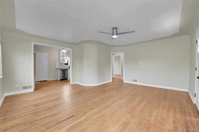 unfurnished living room with ceiling fan, light wood-type flooring, and baseboards