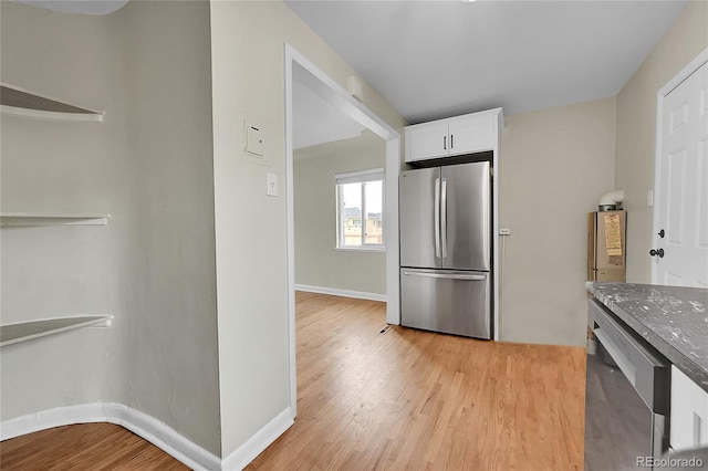 kitchen with appliances with stainless steel finishes, light wood-type flooring, white cabinets, and dark stone counters