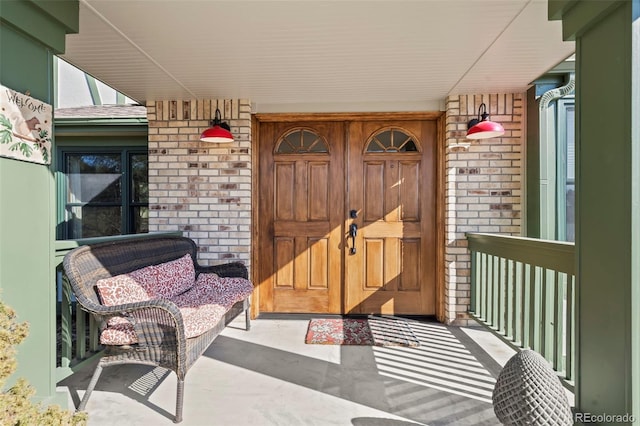 property entrance featuring covered porch and brick siding