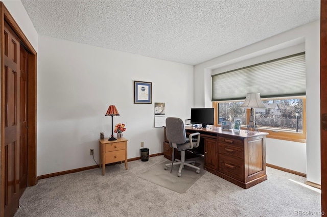 office featuring baseboards, a textured ceiling, and light colored carpet