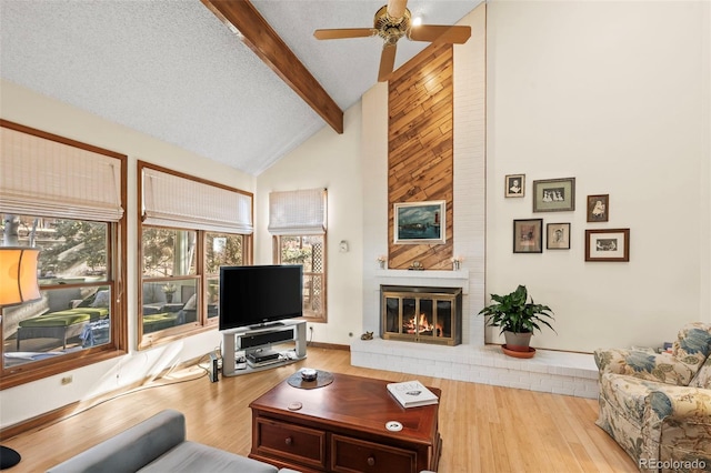 living room featuring a brick fireplace, a textured ceiling, wood finished floors, high vaulted ceiling, and beamed ceiling