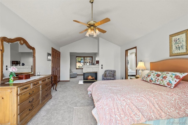 bedroom featuring a ceiling fan, a glass covered fireplace, light carpet, and vaulted ceiling