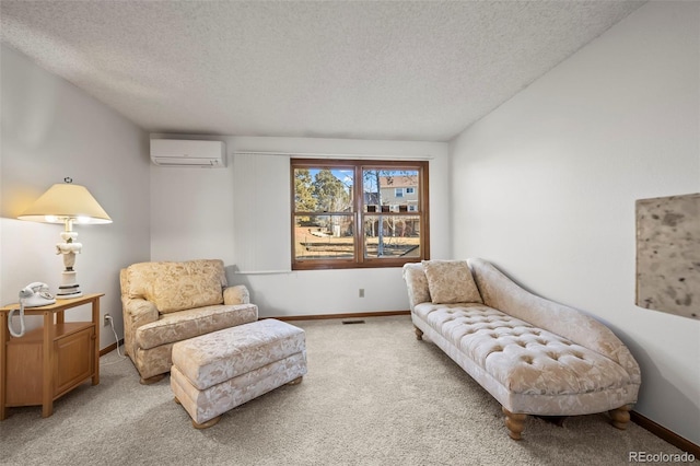 sitting room with a wall unit AC, light colored carpet, visible vents, a textured ceiling, and baseboards