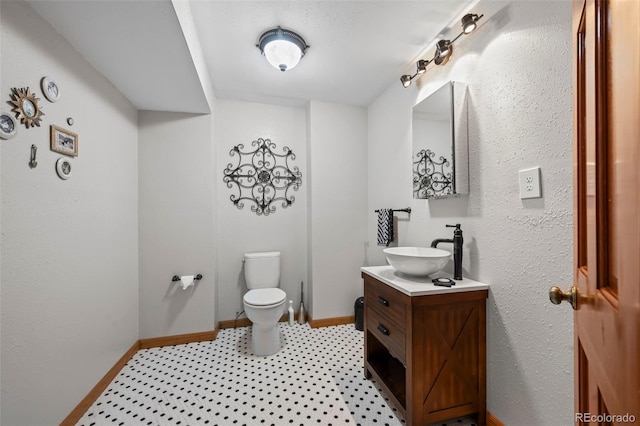 bathroom featuring vanity, toilet, and baseboards