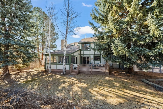 back of house featuring a shingled roof, a chimney, a wooden deck, and a sunroom