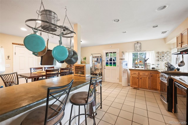 kitchen featuring a breakfast bar, stainless steel appliances, light tile patterned floors, and kitchen peninsula