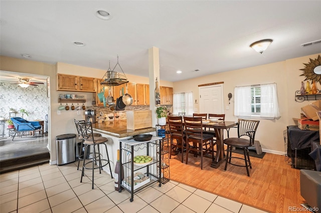 kitchen with light hardwood / wood-style flooring, kitchen peninsula, a kitchen breakfast bar, and ceiling fan