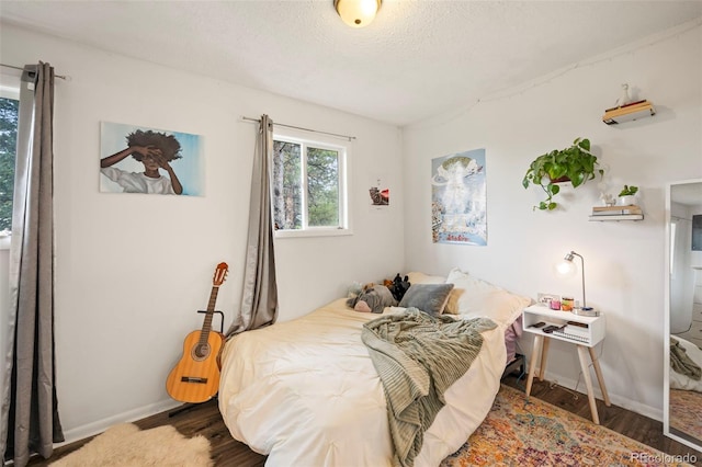 bedroom with dark hardwood / wood-style flooring and a textured ceiling