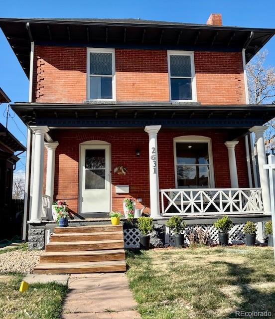 italianate house featuring brick siding, a chimney, a porch, and a front yard