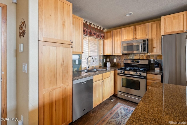 220 Reunion Ct, Fraser, CO 80442 - kitchen featuring appliances with stainless steel finishes, light brown cabinetry, dark countertops, a textured ceiling, and backsplash