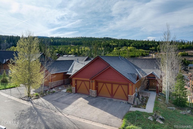 220 Reunion Ct, Fraser, CO 80442 - view of front of house with a view of trees, an attached garage, stone siding, driveway, and a shingled roof