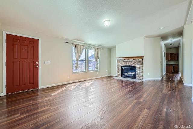 unfurnished living room featuring a textured ceiling, a fireplace, dark wood-type flooring, and vaulted ceiling