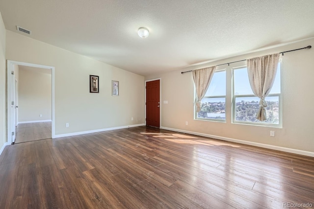 spare room featuring a textured ceiling, dark hardwood / wood-style flooring, and lofted ceiling