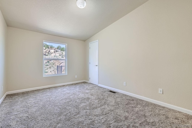 empty room featuring a textured ceiling, carpet floors, and vaulted ceiling