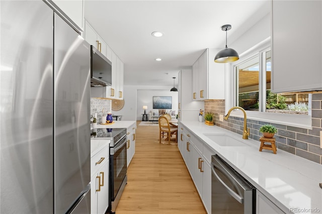 6643 W Roxbury Pl, Littleton, CO 80128 - kitchen featuring stainless steel appliances, tasteful backsplash, decorative light fixtures, light wood-style flooring, and white cabinetry