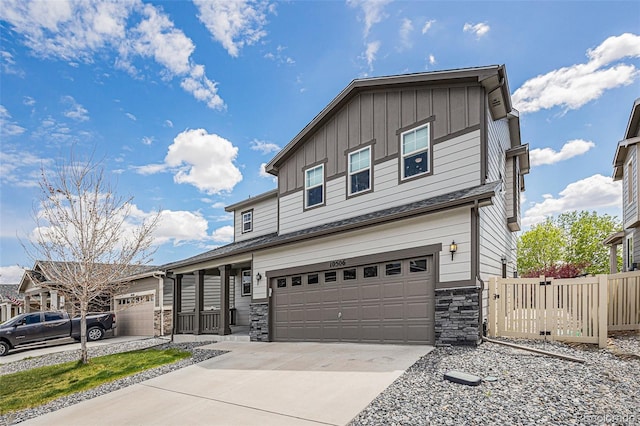 traditional home with board and batten siding, stone siding, driveway, and a garage