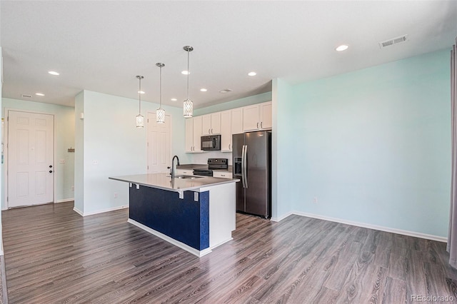kitchen featuring dark wood-style floors, black appliances, visible vents, and a center island with sink