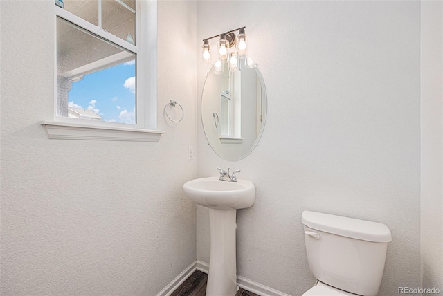 half bath featuring toilet and baseboards