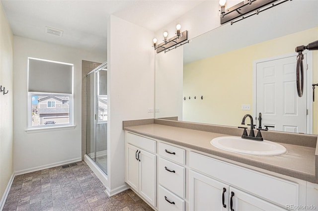 bathroom featuring vanity, baseboards, a shower stall, and visible vents