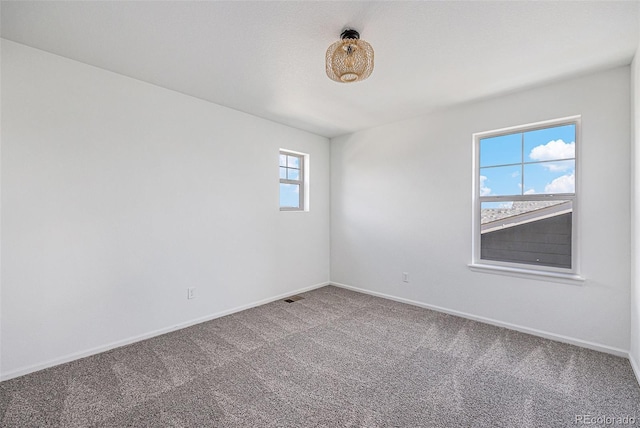 carpeted spare room featuring visible vents and baseboards