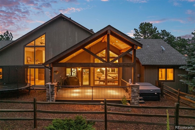 29210 Northstar Ln, Evergreen, CO 80439 - back of house at dusk with a trampoline, a shingled roof, and covered porch