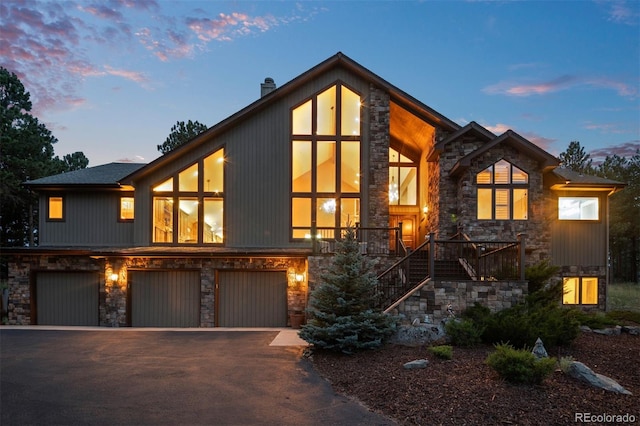 29210 Northstar Ln, Evergreen, CO 80439 - modern home with stone siding, stairway, a chimney, asphalt driveway, and an attached garage