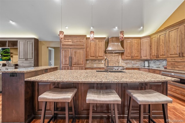 29210 Northstar Ln, Evergreen, CO 80439 - kitchen featuring custom range hood, an island with sink, decorative backsplash, light stone counters, and vaulted ceiling