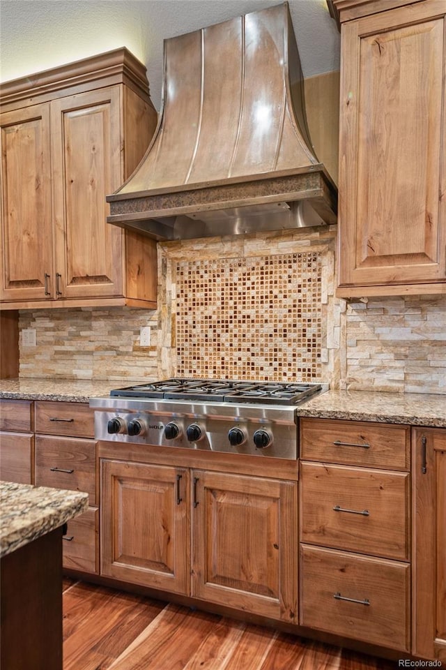 29210 Northstar Ln, Evergreen, CO 80439 - kitchen featuring premium range hood, stainless steel gas stovetop, tasteful backsplash, light stone countertops, and wood finished floors