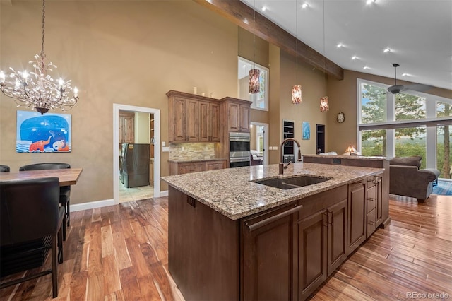 29210 Northstar Ln, Evergreen, CO 80439 - kitchen with high vaulted ceiling, open floor plan, wood finished floors, a chandelier, and light stone counters