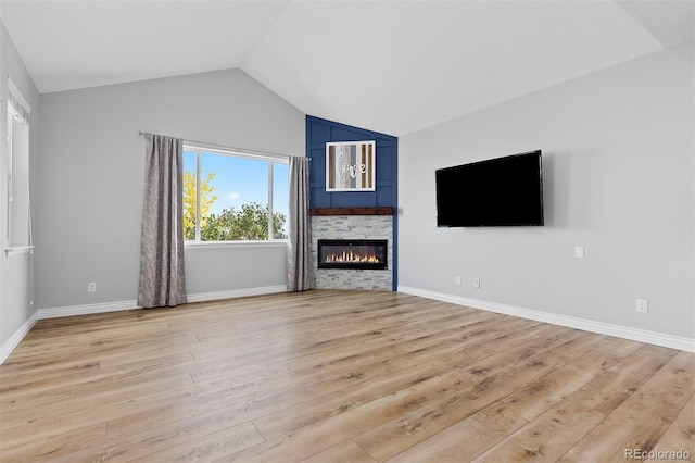 11343 E 163rd Ct, Brighton, CO 80602 - unfurnished living room featuring lofted ceiling, light wood finished floors, a glass covered fireplace, and baseboards