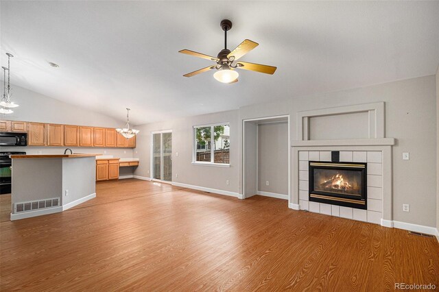 5214 S Tibet St, Aurora, CO 80015 - unfurnished living room featuring vaulted ceiling, light wood-style floors, a chandelier, ceiling fan, and a tiled fireplace