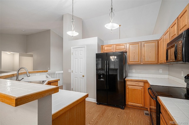 5214 S Tibet St, Aurora, CO 80015 - kitchen featuring black appliances, tile counters, light wood-style flooring, vaulted ceiling, and a sink