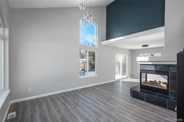 living room featuring hardwood / wood-style flooring, a tiled fireplace, and a high ceiling