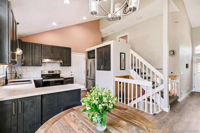 3612 Rosewalk Cir, Highlands Ranch, CO 80129 - kitchen with appliances with stainless steel finishes, under cabinet range hood, high vaulted ceiling, light countertops, and backsplash
