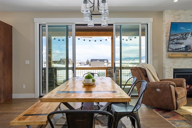 dining area featuring a fireplace, baseboards, and wood finished floors