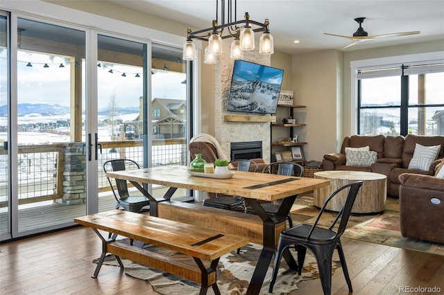 dining space with light wood-style floors, a mountain view, a fireplace, and ceiling fan