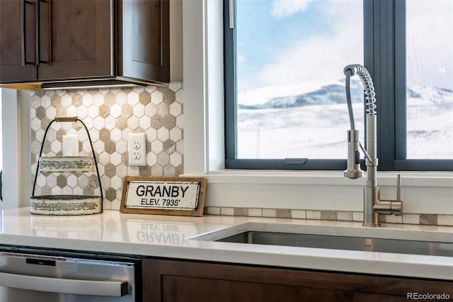 kitchen featuring dark brown cabinetry, dishwasher, backsplash, light countertops, and a sink