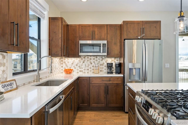 kitchen featuring stainless steel appliances, a sink, a wealth of natural light, and decorative backsplash