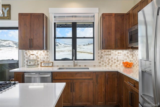 kitchen featuring stainless steel appliances, light countertops, a sink, and tasteful backsplash