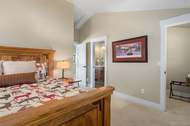 bedroom featuring light carpet, vaulted ceiling, ensuite bathroom, and baseboards