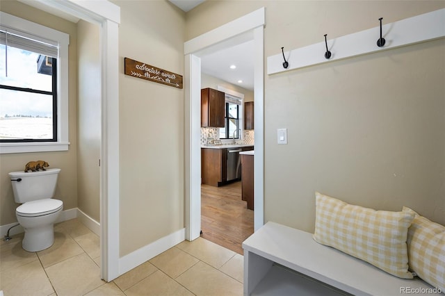 mudroom featuring a healthy amount of sunlight, light tile patterned floors, and baseboards