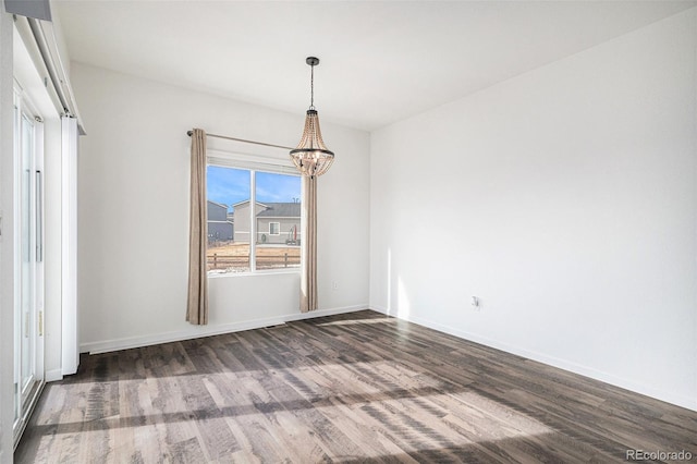 unfurnished dining area featuring dark wood-type flooring and a chandelier